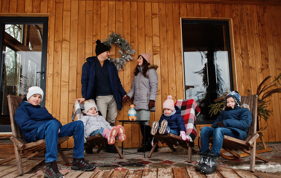 Une famille assise sur un banc devant un chalet, profitant d'un moment de détente en pleine nature.
