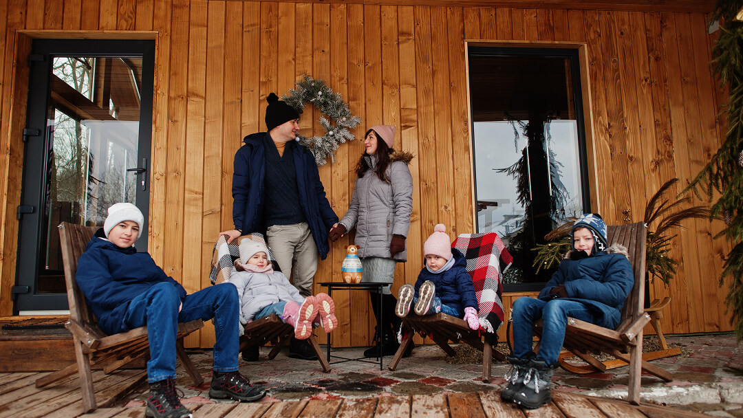 Une famille assise sur un banc devant un chalet, profitant d'un moment de détente en pleine nature.