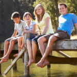 Une famille assise sur un quai au bord d'un lac, profitant d'un moment de camping au Québec.