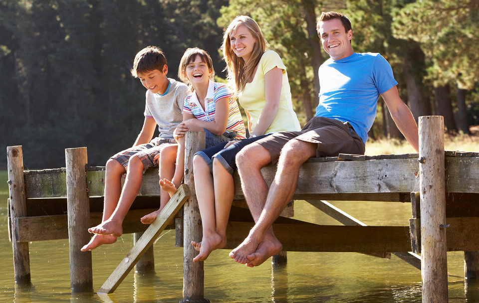 Une famille assise sur un quai au bord d'un lac, profitant d'un moment de camping au Québec.
