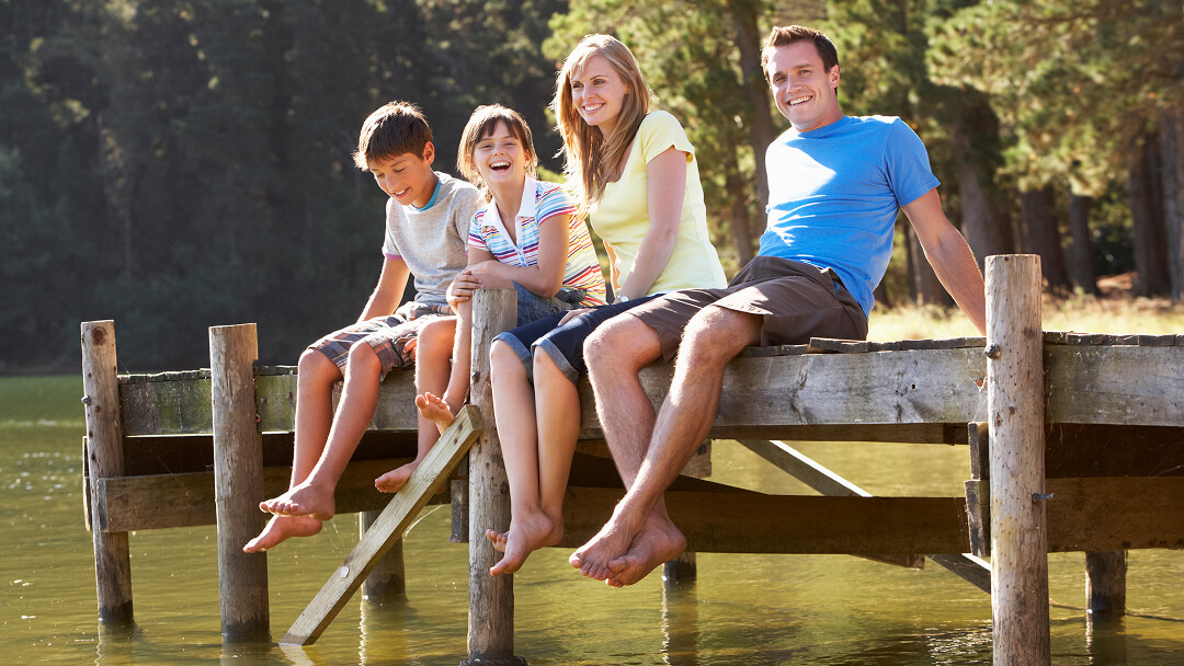 Une famille assise sur un quai au bord d'un lac, profitant d'un moment de camping au Québec.