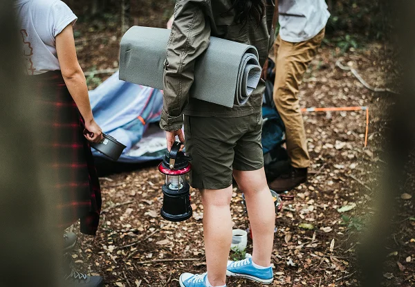 Un groupe de personnes se tient autour d'une tente lors d'une activité de camping prêt à camper.
