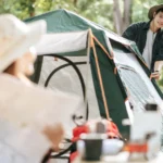 Un homme et une femme se tiennent devant une tente sur un terrain de camping.
