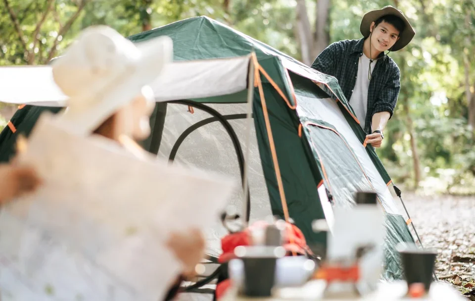 Un homme et une femme se tiennent devant une tente sur un terrain de camping.