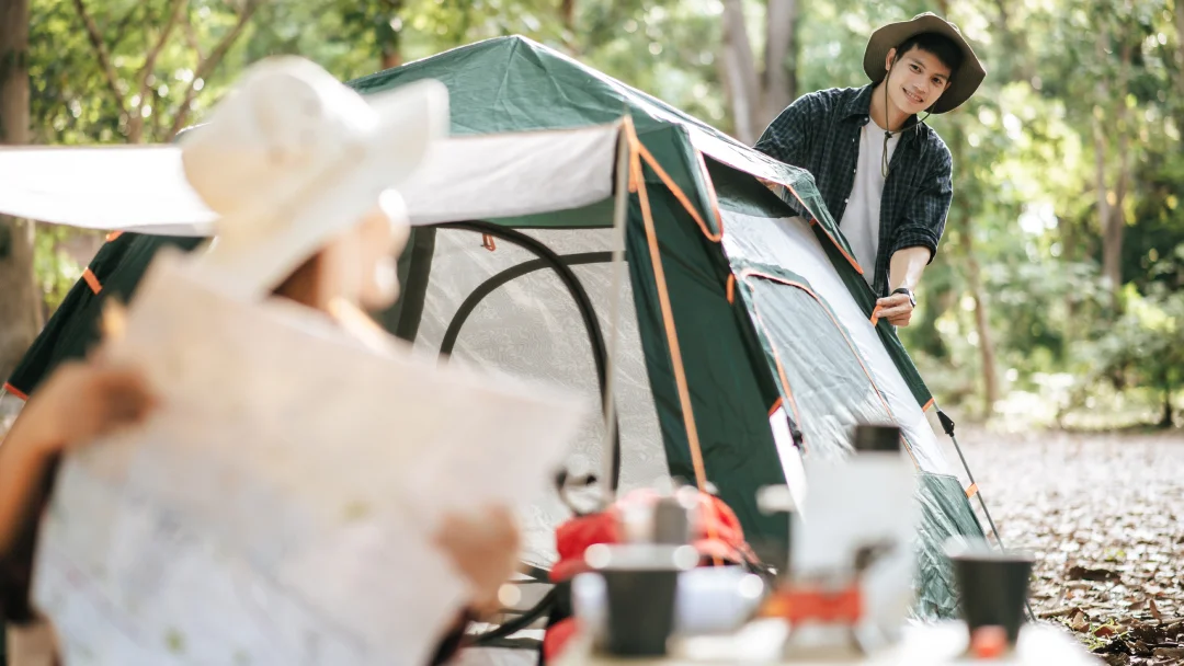 Un homme et une femme se tiennent devant une tente sur un terrain de camping.